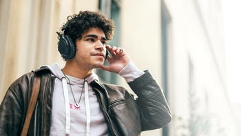 A young man walking on the street with his headphones on.