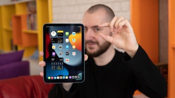 Sixth-gen iPad mini is held by a person in portrait mode while making a "small" gesture with index finger and thumb