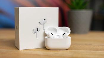 AirPods Pro 2 in its charging case next to the original box, placed on a wooden table.