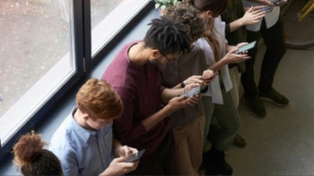 People standing next to each other, each using their smartphones.