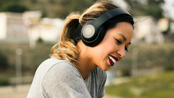 A woman smiling while wearing black Beats Studio3 headphones