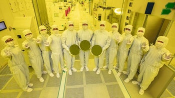 Wearing protective suits, Samsung Foundry employees hold silicon wafers under the special yellow lights.