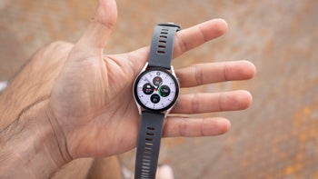 A close-up of a man holding the Galaxy Watch 6 with a Graphite band.