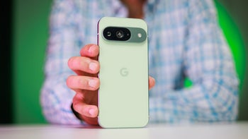 Google Pixel 9 in green placed on a table with its back towards us.