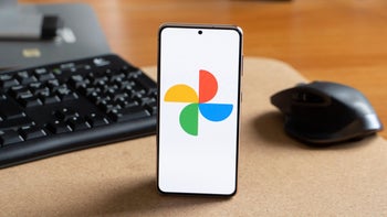 Google Photos logo displayed on a smartphone screen resting on a wooden table.