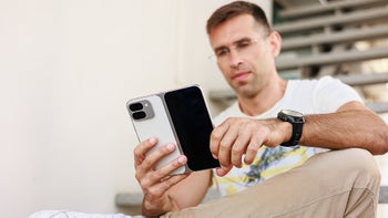 A person sitting and reading something on a foldable phone.