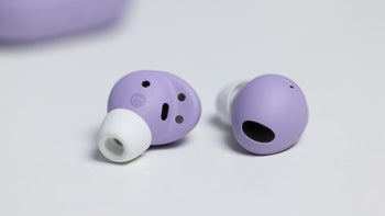 Two purple Galaxy Buds 2 Pro earbuds with white silicone tips lie on a white surface.