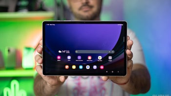 A person holding a Galaxy Tab S9 with the display on.