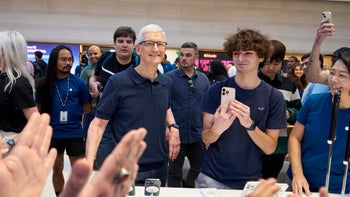 Tim Cook standing next to a customer at the Fifth Avenue Apple Store holding a new iPhone 16 Pro series handset.