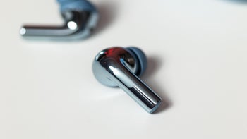 Close-up of the OnePlus Buds 3 in Splendid Blue, placed on a table against a blurred background.