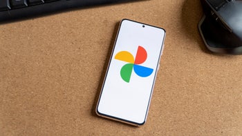 An image of an Android phone laying on a table displaying the Google Photos app logo