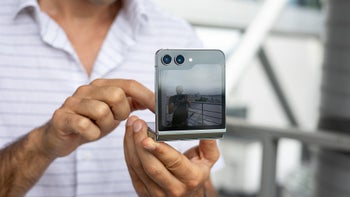 A person holding the Galaxy Z Flip 5 in its folded state, showing the external display and the dual rear cameras.