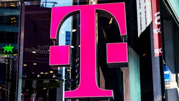 The T-Mobile "T" logo in magenta is seen as part of a sign mounted on a building.