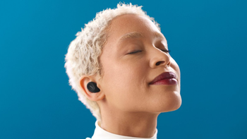 A woman with short hair and closed eyes enjoying music on the Jabra Elite 10. She stands against a blue background.