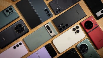 A collection of high-end smartphones arranged side-by-side on a wooden surface.