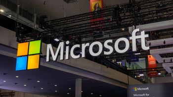 The Microsoft wordmark and logo hand near the ceiling during a convention.