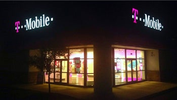 A T-Mobile corner location storefront lit up at night with the signs and the lighting from inside the store.