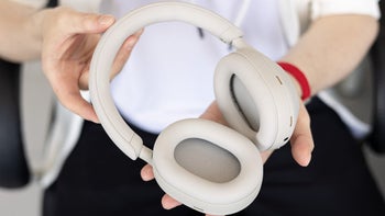 A person holding a set of Sony WH-1000XM5 headphones