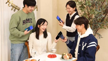 A group of smiling South Korean young people that are engaged in sending money to each other wirelessly via their Galaxy phones.