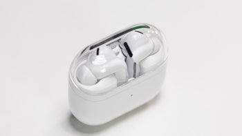 The Galaxy Buds 3 Pro in White are placed in their charging case with a transparent lid, which stands on a white table.