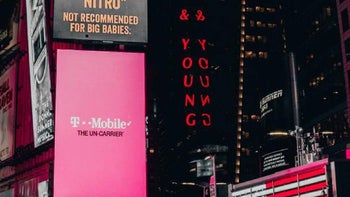 Digital billboard displays an ad for T-Mobile with white and black lettering on a magenta background.