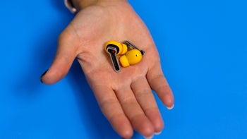 A close-up of a palm holding the Nothing Ear (a) wireless earbuds in Yellow.