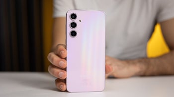 Close-up of a person holding the Awesome Lilac-coated Galaxy A35 upright on a table, showing its rear glass back design.