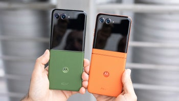 A person holding two Motorola Razr foldable smartphones, one in green and one in orange.