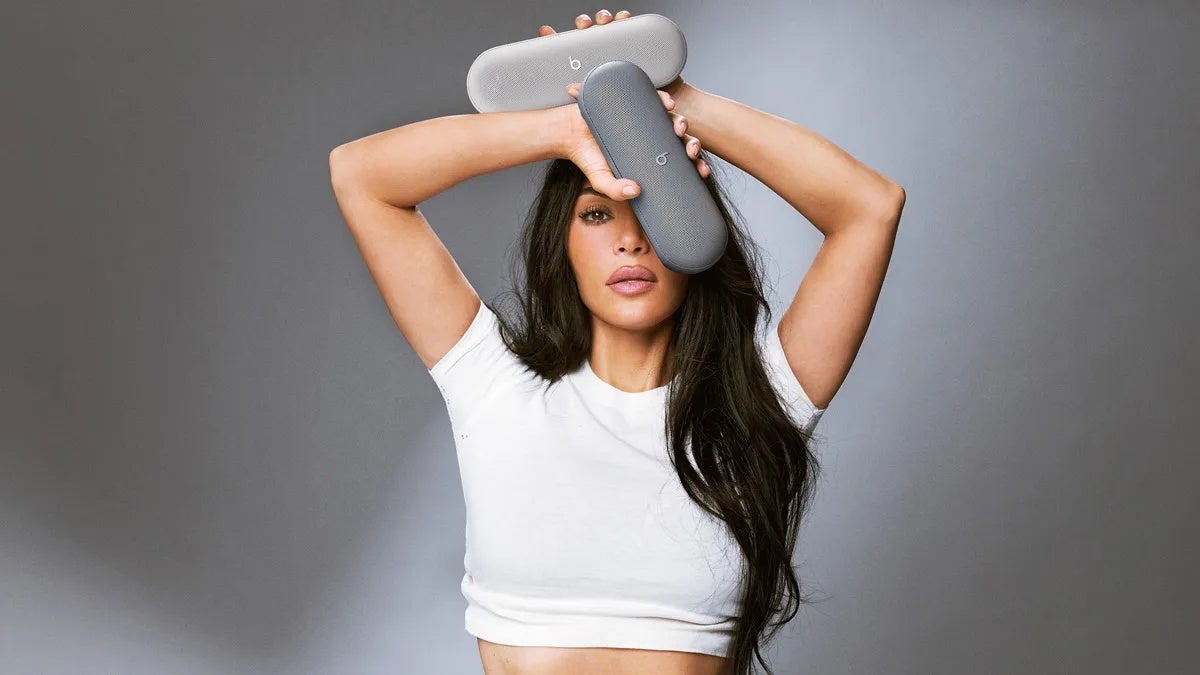Kim Kardashian holding two Beats Pill speakers in dark gray and light gray colors