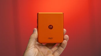 A close-up of a hand holding the Motorola Razr (2024) in Spritz Orange, showcasing the phone's vegan leather back.