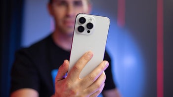 An iPhone in a person's hand on a blurry background.