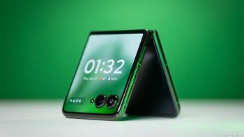 A close-up of the Razr+ (2024), half-folded with the screen turned on, against a bright green background.