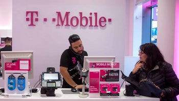 Inside a T-Mobile store we see a rep on the phone while a customer waits on line.