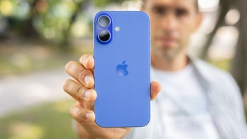 A person holding the iPhone 16 in blue on a sunny day outside.