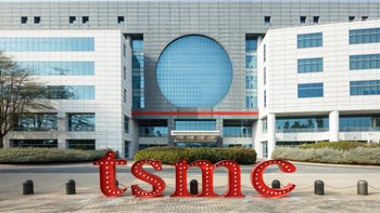 TSMC logo is lower case letters sits on the ground in front of one of the Foundry's fabs.