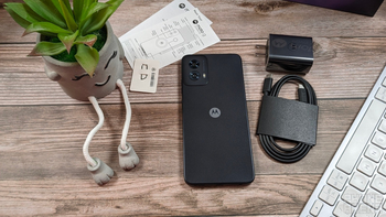 The Moto G Power 5G (2024) is arranged alongside a charging cable and other in-the-box items on a wooden surface.