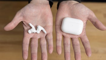 A person's hands holding a pair of AirPods Pro and its charging case.