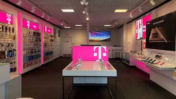 The inside of a T-Mobile store is seen with magenta colored signs and shelves.