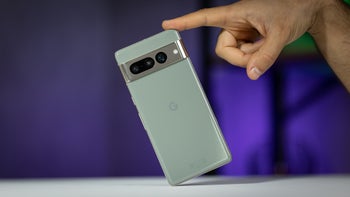 Pixel 7 Pro in Hazel, held upright by a hand against a blurred purple background.