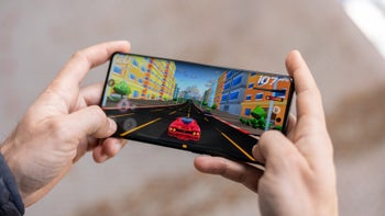 Hands holding the Motorola Edge+ (2023), displaying a colorful racing game against a blurred background.