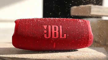 JBL Charge 5 in Red with wood flakes appearing to fall on top of it.