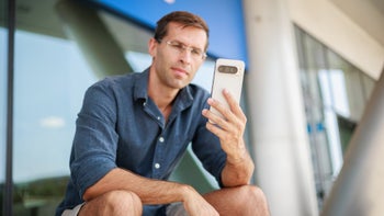 PhoneArena's Vic sits on some stairs while looking at the screen of the Pixel 9 Pro XL.