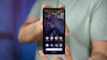 A close-up of a person who holds the Pixel 7a, showcasing the phone's display and home screen.