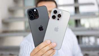 PhoneArena's Vic holds up to the camera the rear panels of the iPhone 16 Pro and iPhone 16 Pro Max.