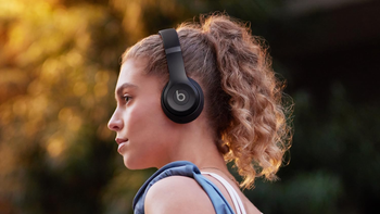 A woman with a ponytail and a big handbag on her left shoulder is wearing the Beats Solo 4 in Matte Black outdoors.