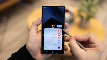 The front of the Galaxy S24 Ultra is seen with the user holding the pphone in his left hand and the S Pen in his right hand.