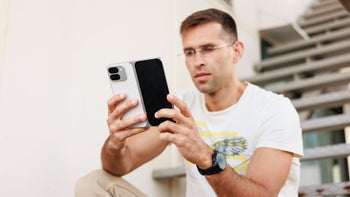 A man seated outdoors, holding the Pixel 9 Pro Fold open, examining its design and display.