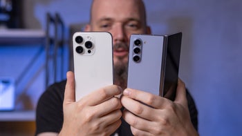 The iPhone 15 Pro Max and the Galaxy Z Fold 5 next to each other held by a person.