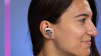 A close-up of a smiling woman with long dark hair wearing the Nothing Ear wireless earbuds.