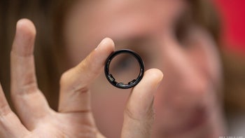 A woman holding the Galaxy Ring in front of her face.